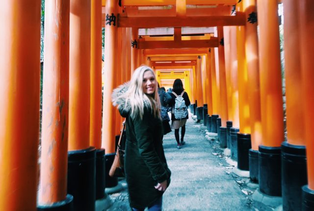 A student on a study away trip to Japan standing under Torri gates