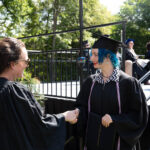 Anna Welton shakes a graduate's hand. The grad is smiling