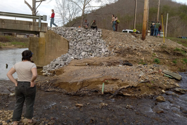Students stand on the washout of a riverbank in Kentucky.
