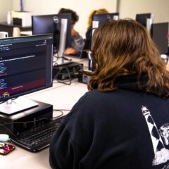 A Data science student codes at a computer.