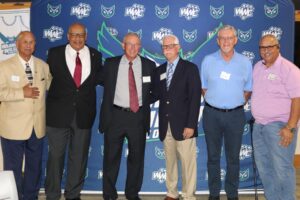 People gather together for a photo in front of the Warren Wilson Athletics press board.