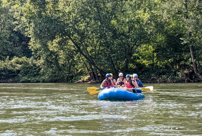 Students in a raft paddling down a river.