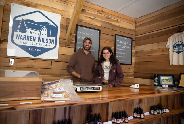 Two people stand smiling behind the counter of the Farm General Store