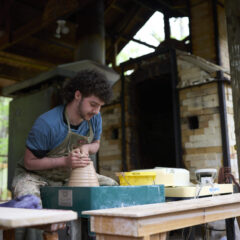 A ceramics student shapes clay on a pottery wheel.