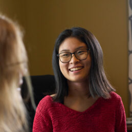 A student is turning their computer towards their advisor to show them what they've been working on with a smile.