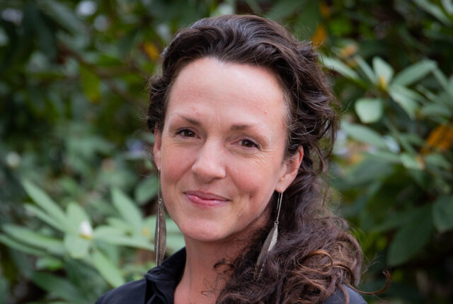 Staff member Anna Welton stands and smiles for her headshot.